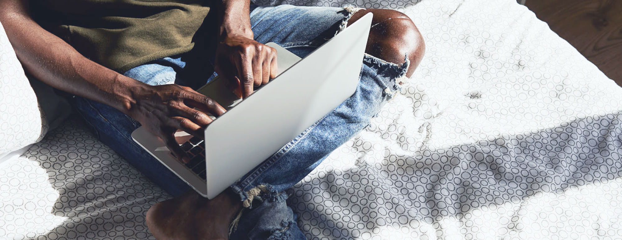 Young man using laptop in bed to access online doctors through the Maple web app